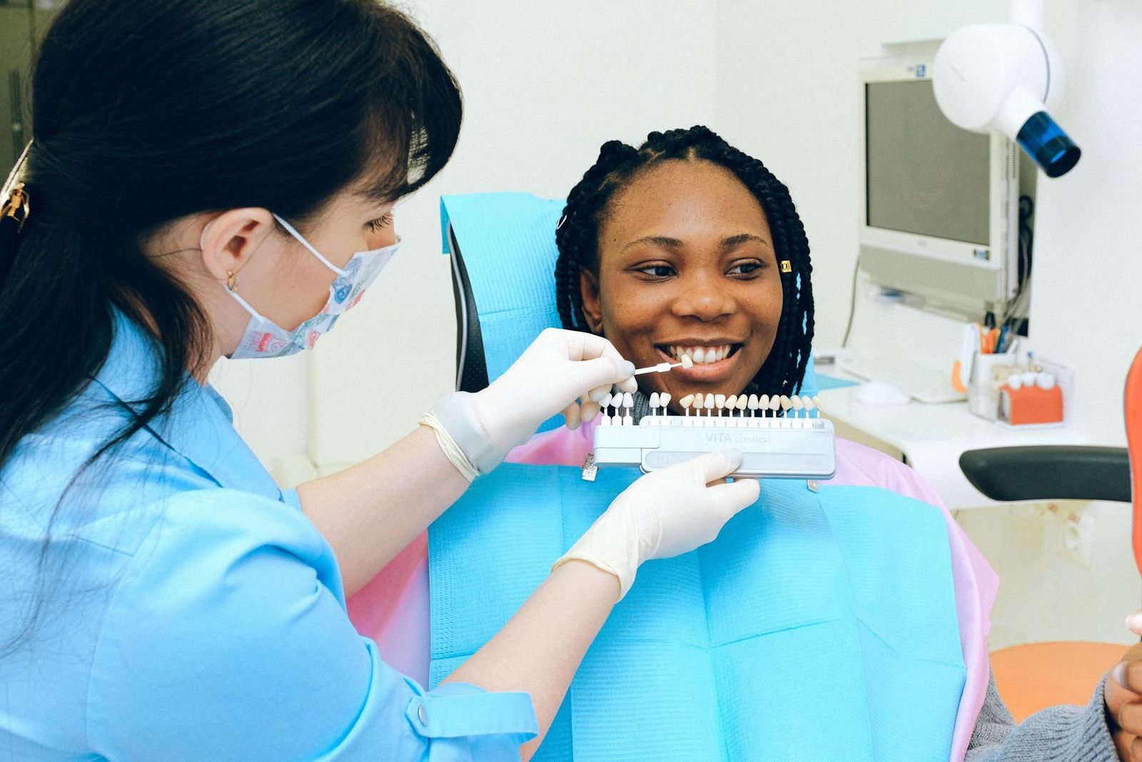 Dentist showing a patient a set of tooth shades during a dental consultation.