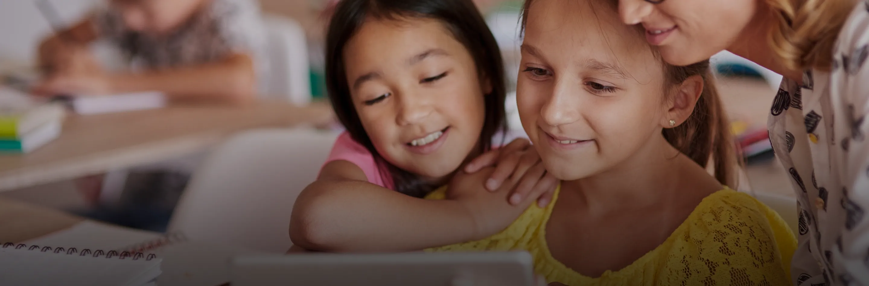 Teacher helping young students with a tablet