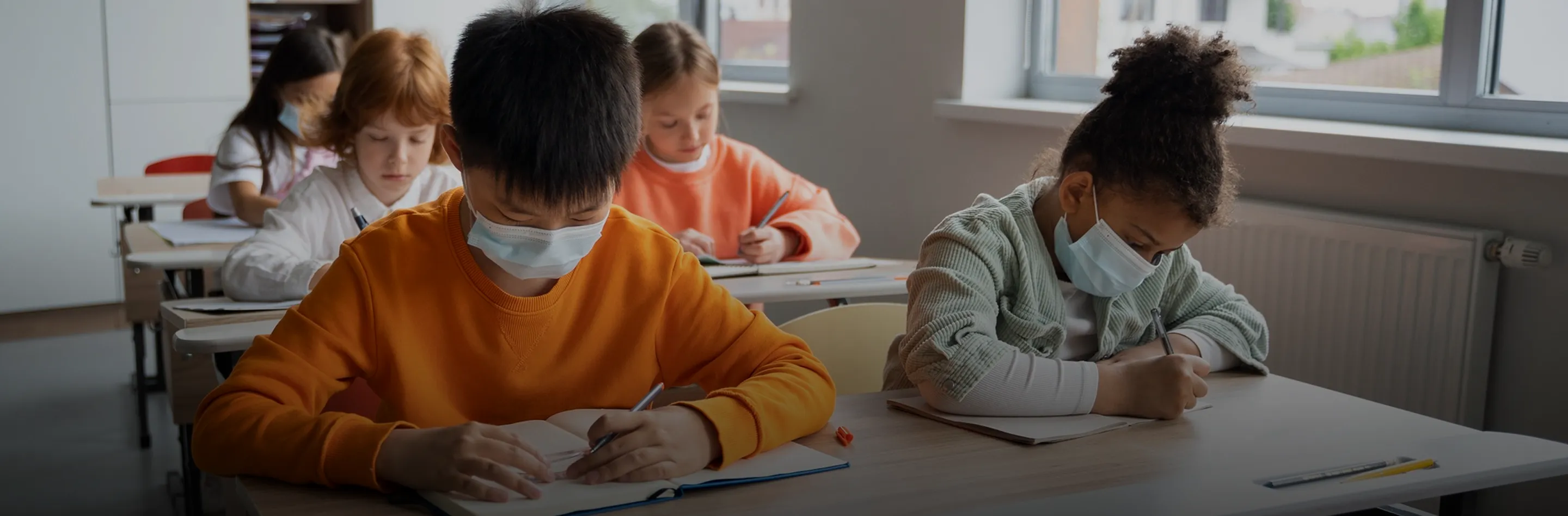 Students wearing face masks working at their desks in a classroom