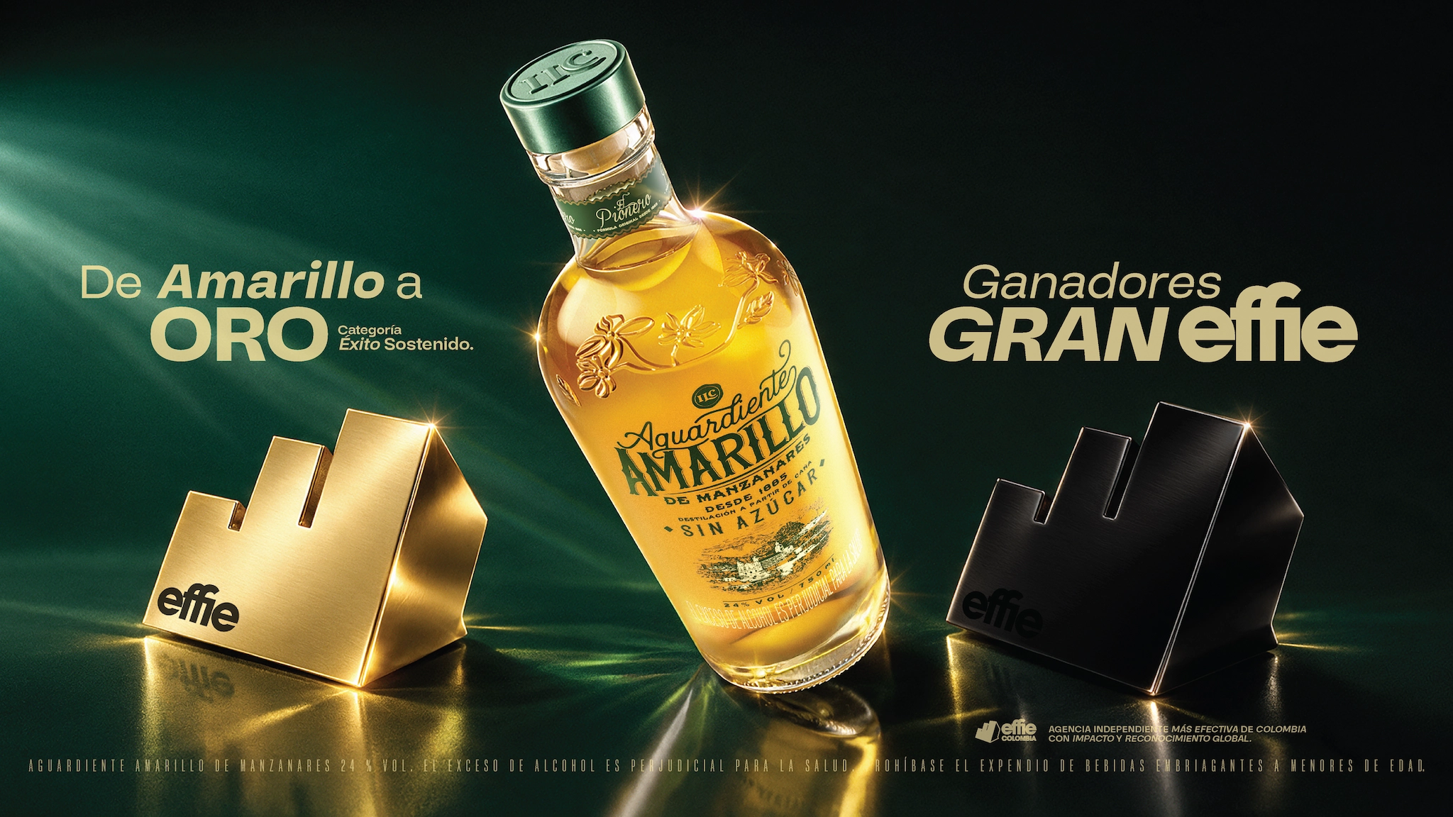 Botella de Aguardiente Amarillo de Manzanares, sin azúcar, con dos trofeos Effie a ambos lados, uno dorado y otro negro, sobre fondo oscuro con texto que destaca el éxito y premio Gran Effie.
