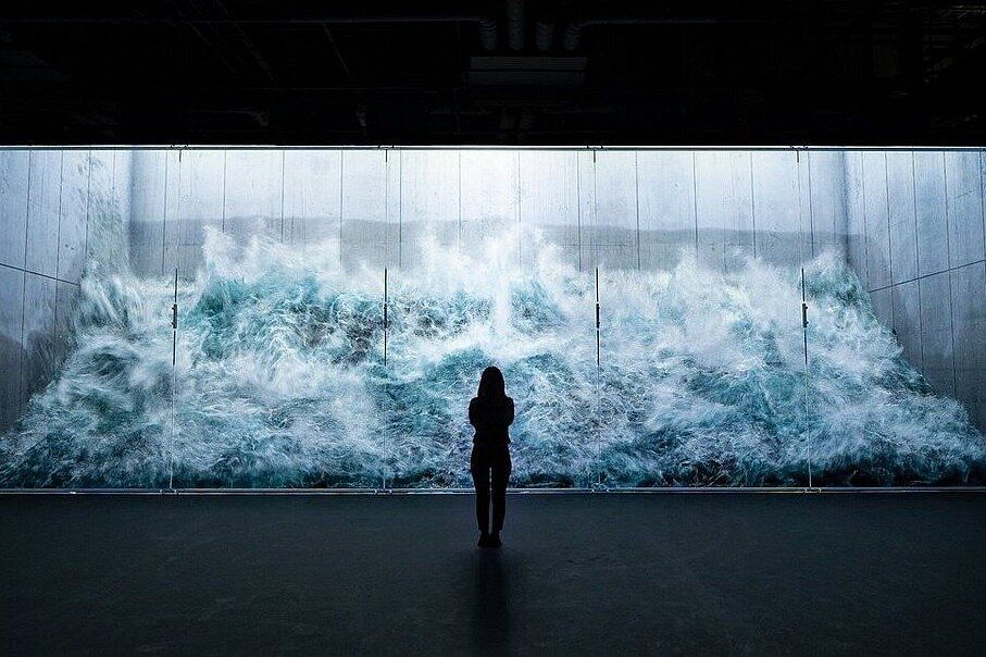 Silhouette einer Person vor einer großen Welle