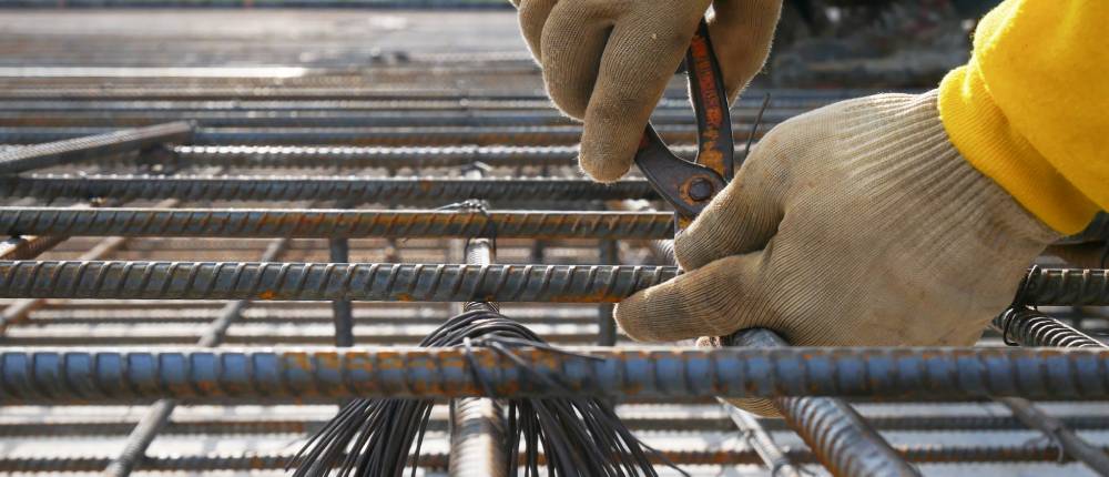 Vakman bindt wapeningsstaal voor een gewapende betonfundering tijdens de voorbereiding van een nieuwbouwproject.