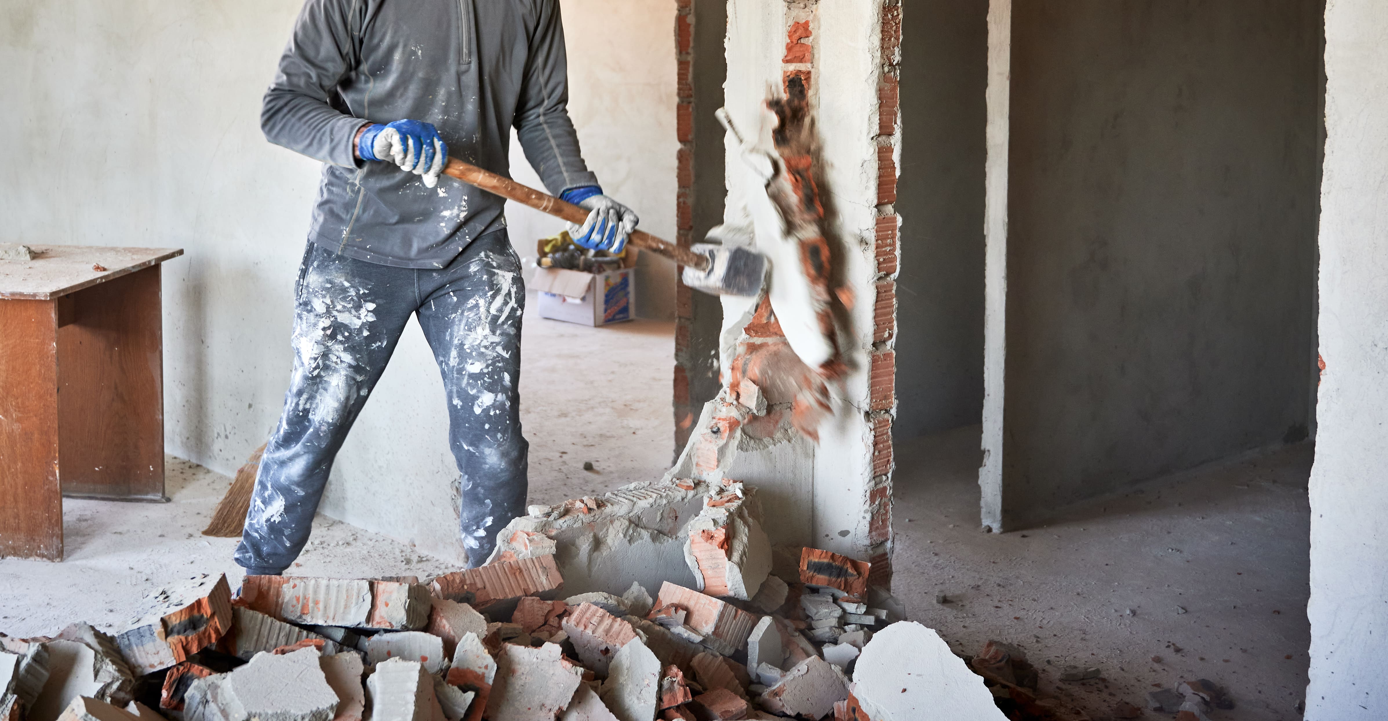 Bouwvakker sloopt een binnenmuur en voert bouwafval af tijdens de renovatie van een woning of bedrijfspand.