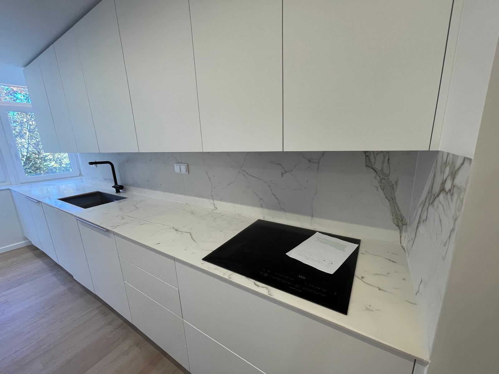 Moderne keuken renovatie met maatwerk kasten en marmerlook werkblad