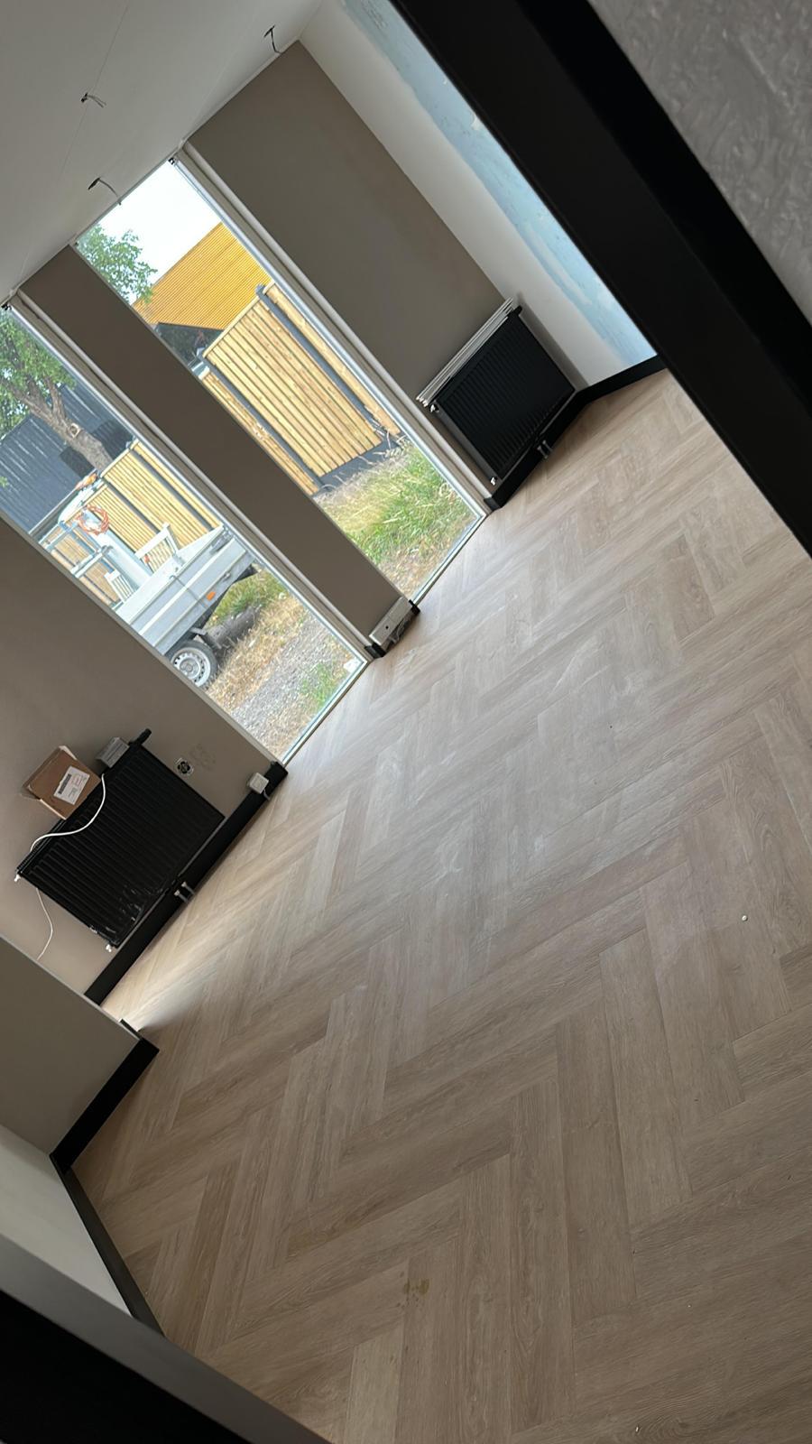 Gerenoveerde woonkamer met visgraatvloer en strak afgewerkte wanden