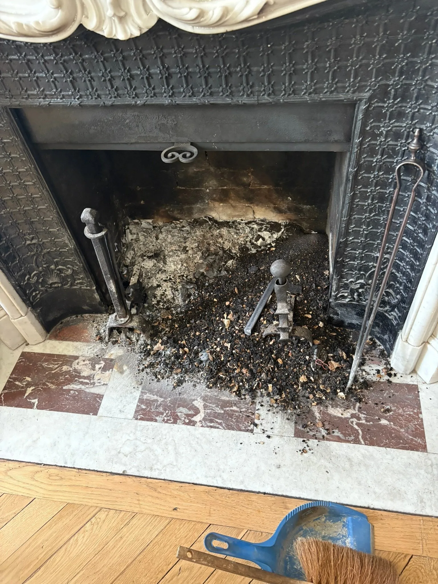 Âtre d'une cheminée ancienne encombré de suie et de gravats avant intervention de ramonage