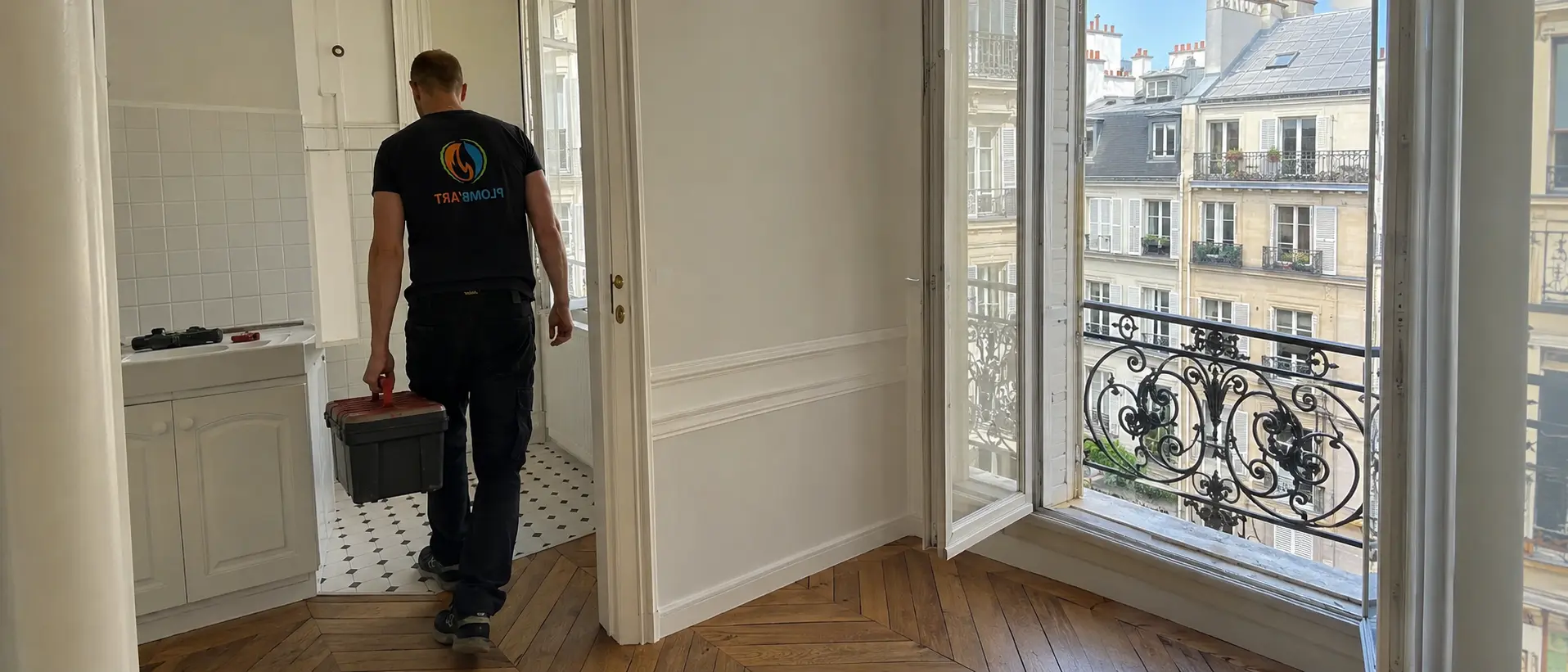 Technicien Plomb'Art traversant un appartement haussmannien vide, caisse à outils à la main
