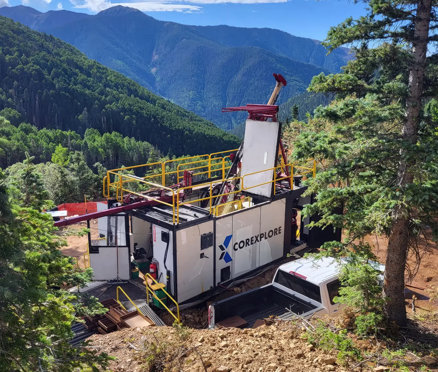Corexplore drill rig and site container at a forested mountain drill site