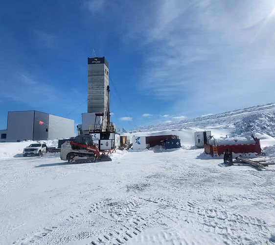 Corexplore drill tower and support vehicles at a snow-covered drill site