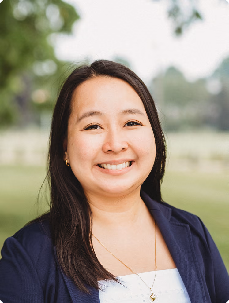 Headshot of April smiling in a navy blazer outdoors