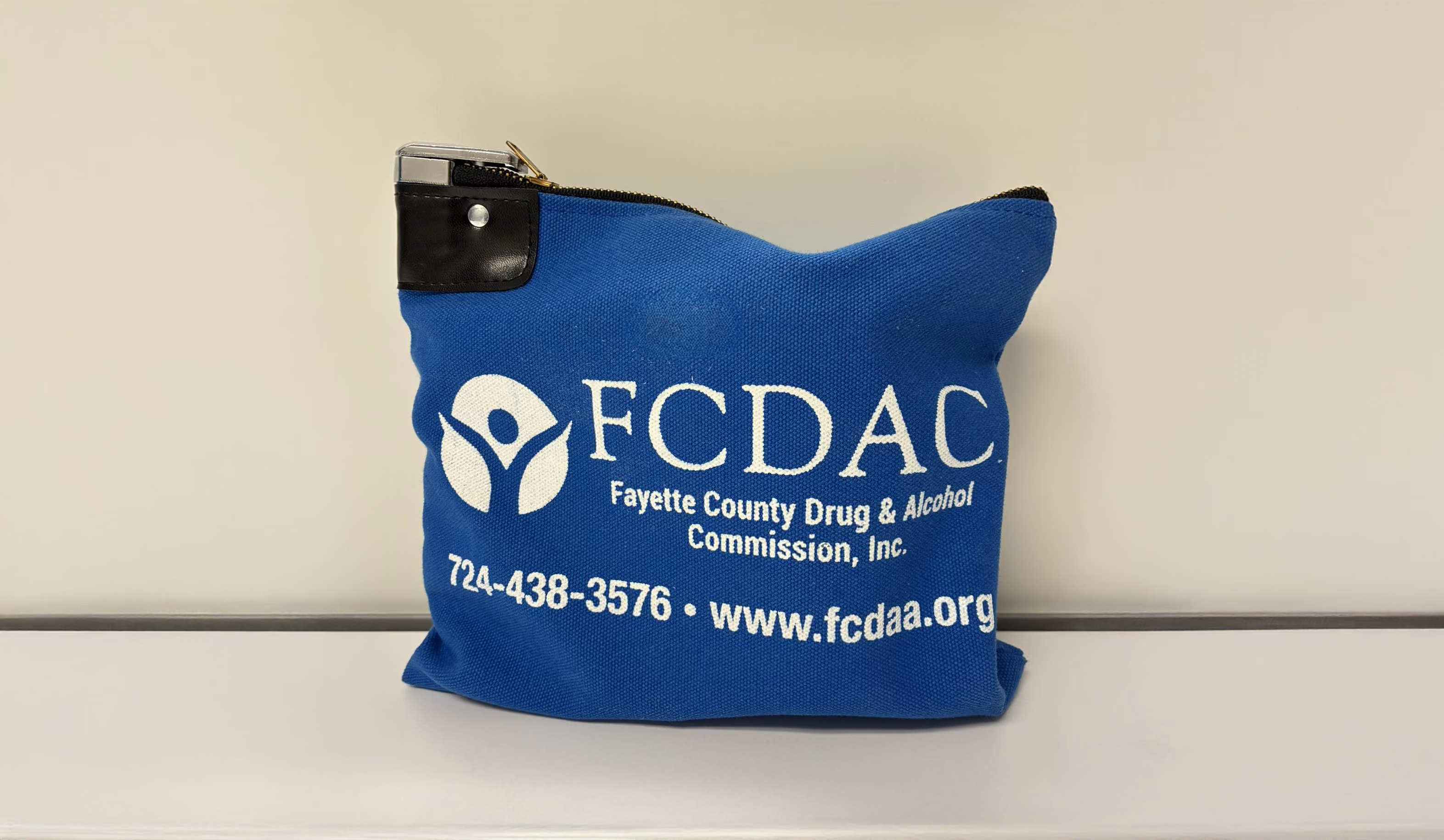 Blue zippered bag with Fayette County Drug & Alcohol Commission logo, phone number, and website.