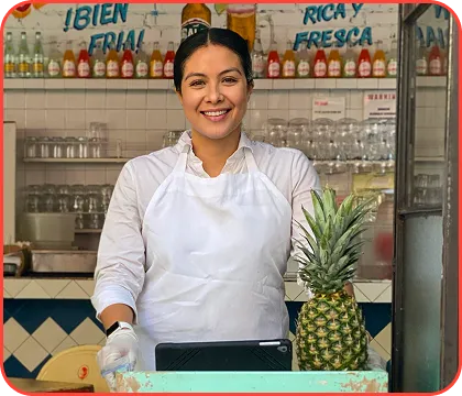 A woman wearing a white apron and holding a pineapple.