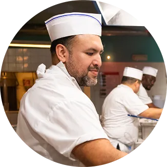 A chef wearing a white hat and apron.