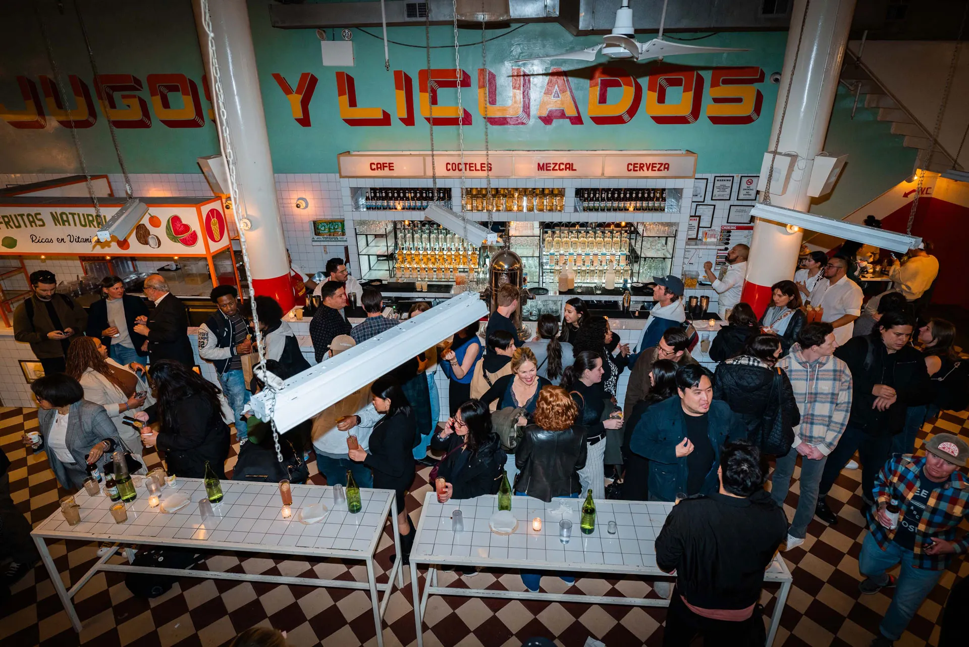 A group of people are standing in a bar with a checkered floor.