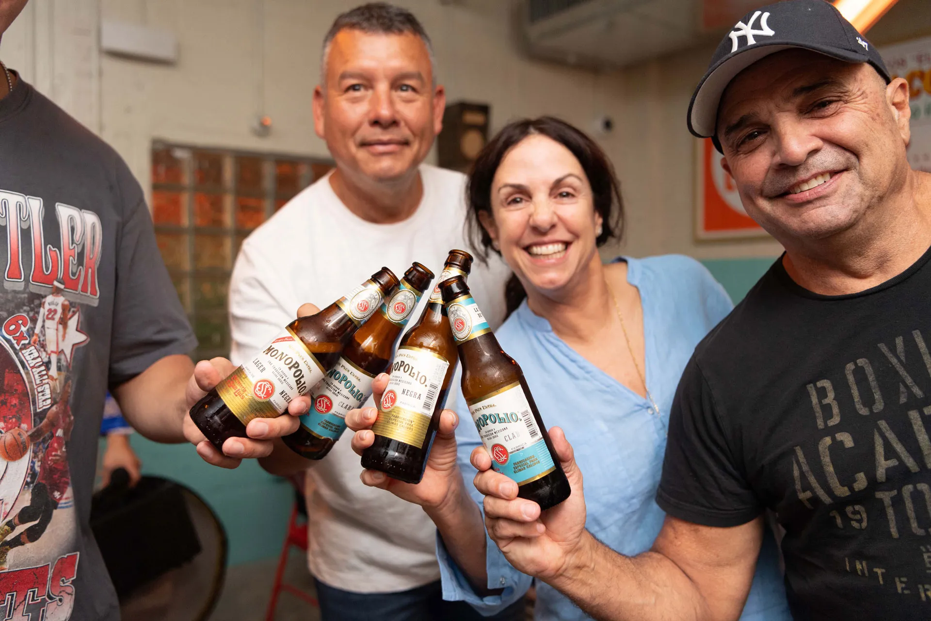 A man and woman holding beers with a man in a black hat.