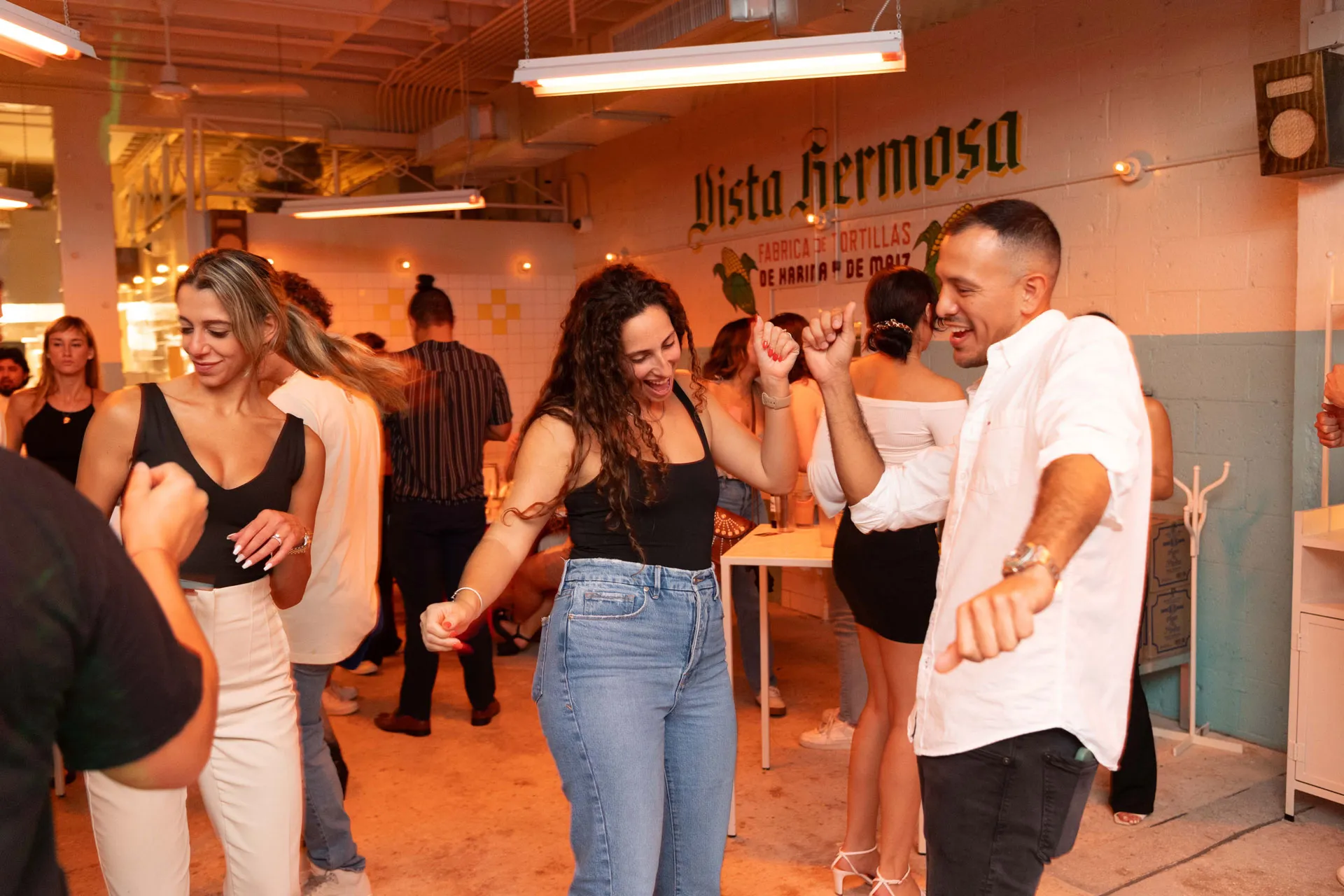 A man and woman are dancing in a room with a sign that says Vista Hermosa.