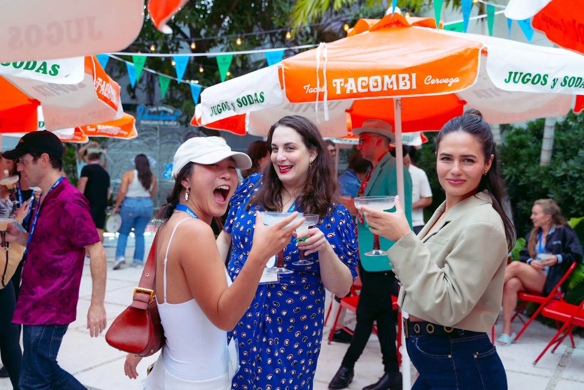 A group of people standing under a large orange umbrella.