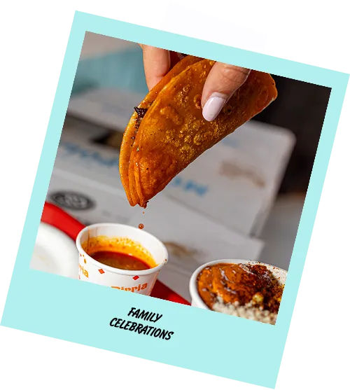 A person is holding a taco over a bowl of soup.
