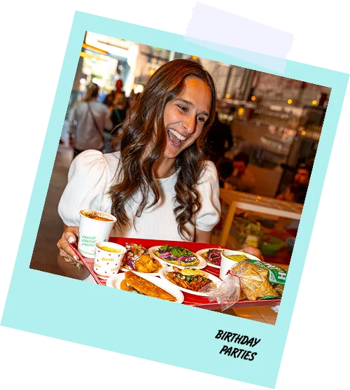 A woman holding a tray of food with a yellow background.