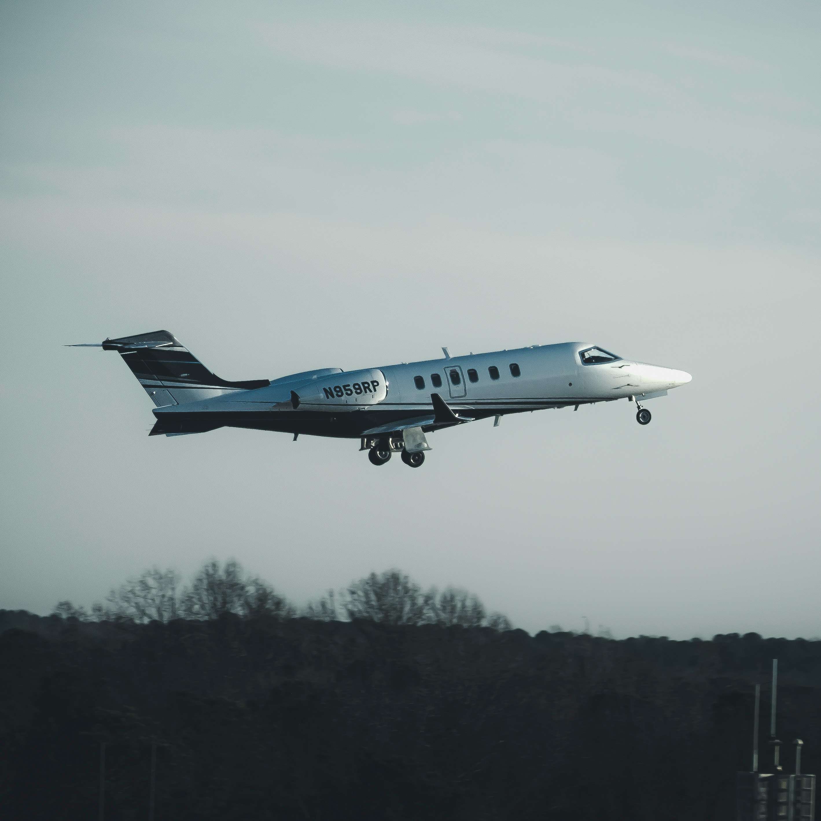 Private jet in flight against a pale sky