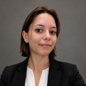 Smilingyoung woman with a white shirt and dark blazer on a gray backdrop