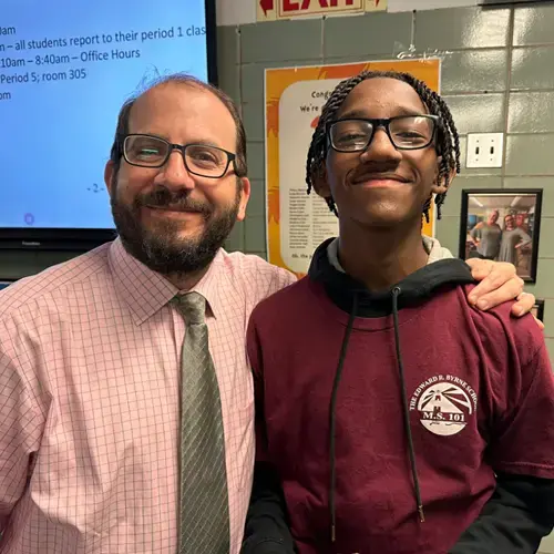 Teacher and MS 101 student smiling together in classroom
