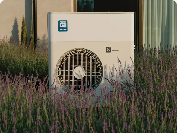 Wärmepumpen-Außeneinheit im Garten vor einem Wohnhaus