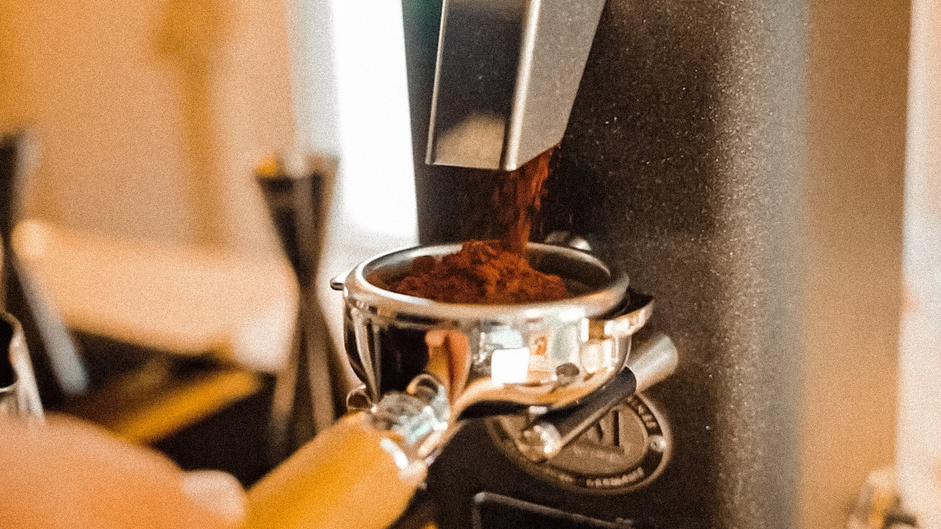 Ground coffee being dispensed into a portafilter from a coffee grinder.