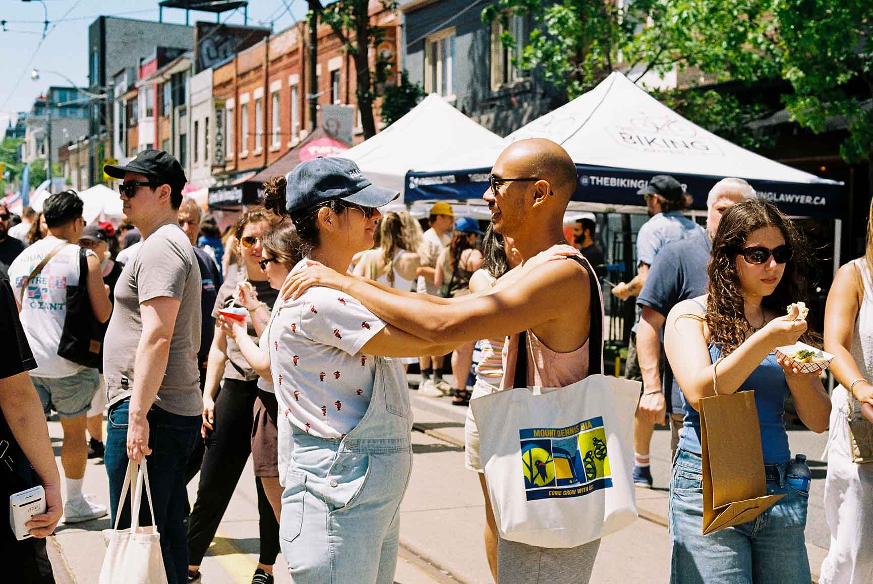 Crowd browsing festival stalls under a tent at Do West Fest