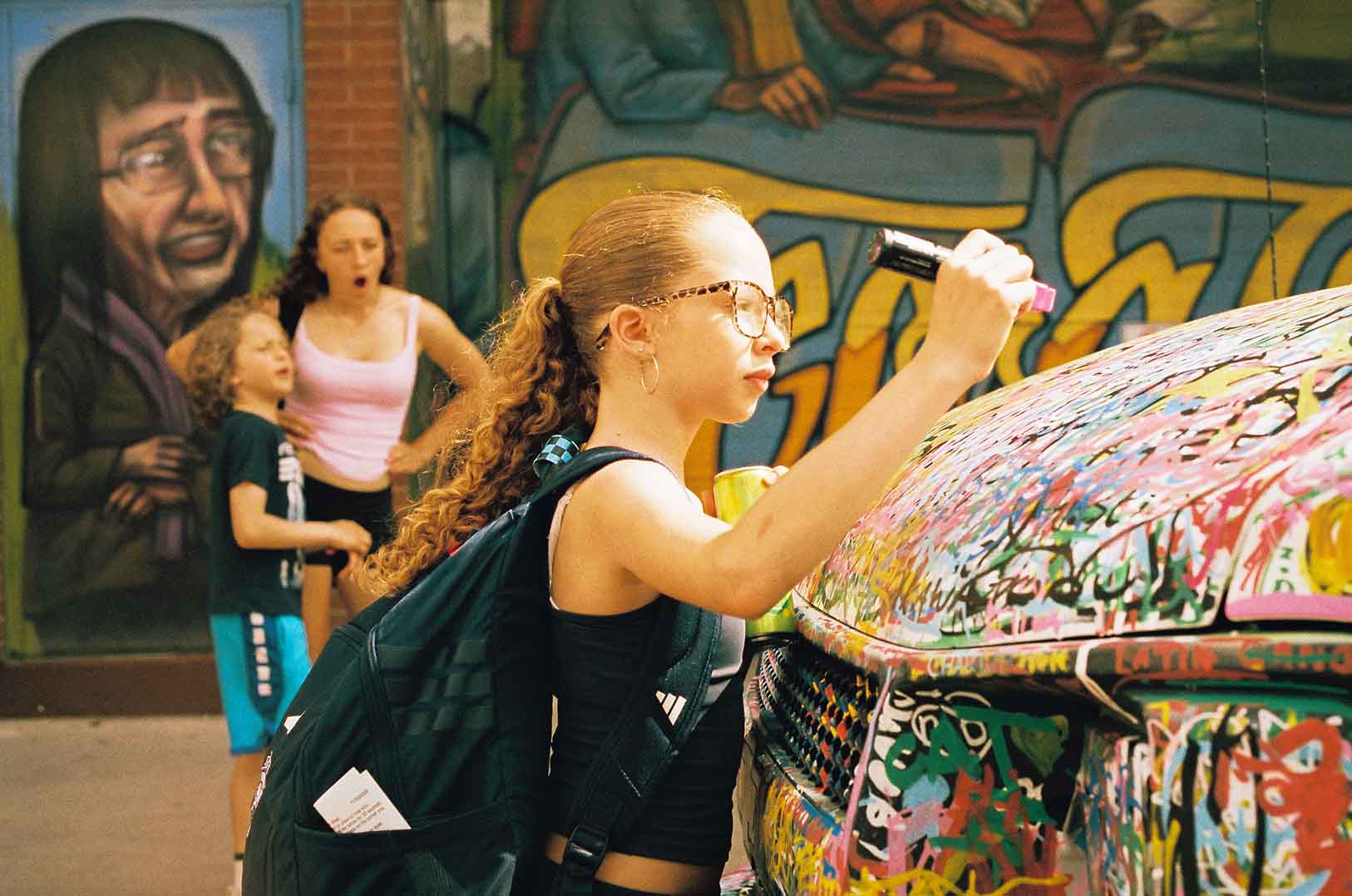 Two musicians performing together in front of a mural at Do West Fest