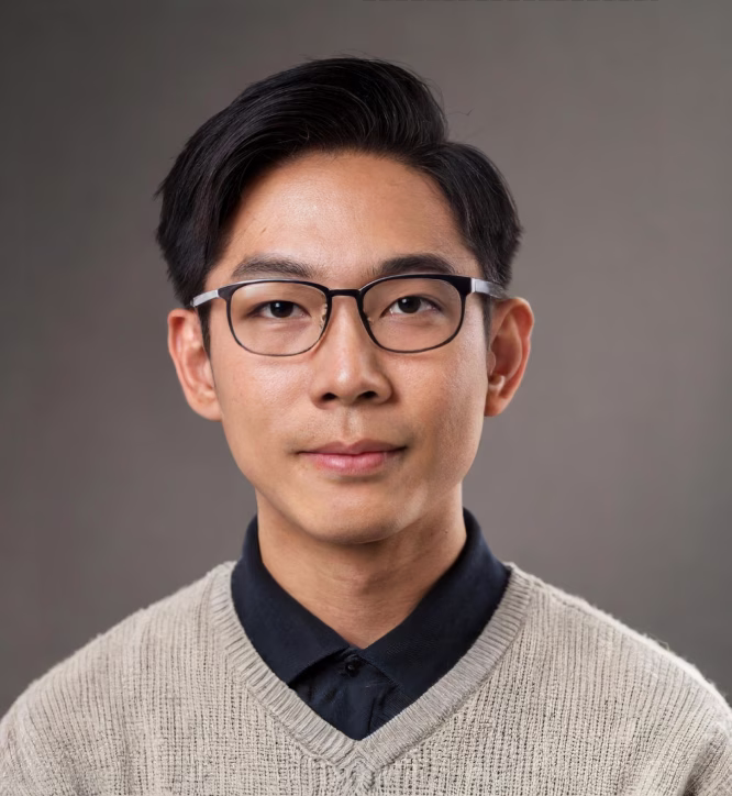 Portrait of a young Asian man with glasses wearing a beige sweater over a black collared shirt against a plain gray background.