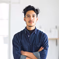 Portrait of a confident young man with folded arms wearing a dark blue shirt in a bright room.