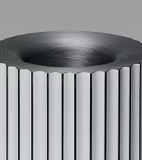 Close-up of a metallic, cylindrical object with vertical ridges and a concave top surface.