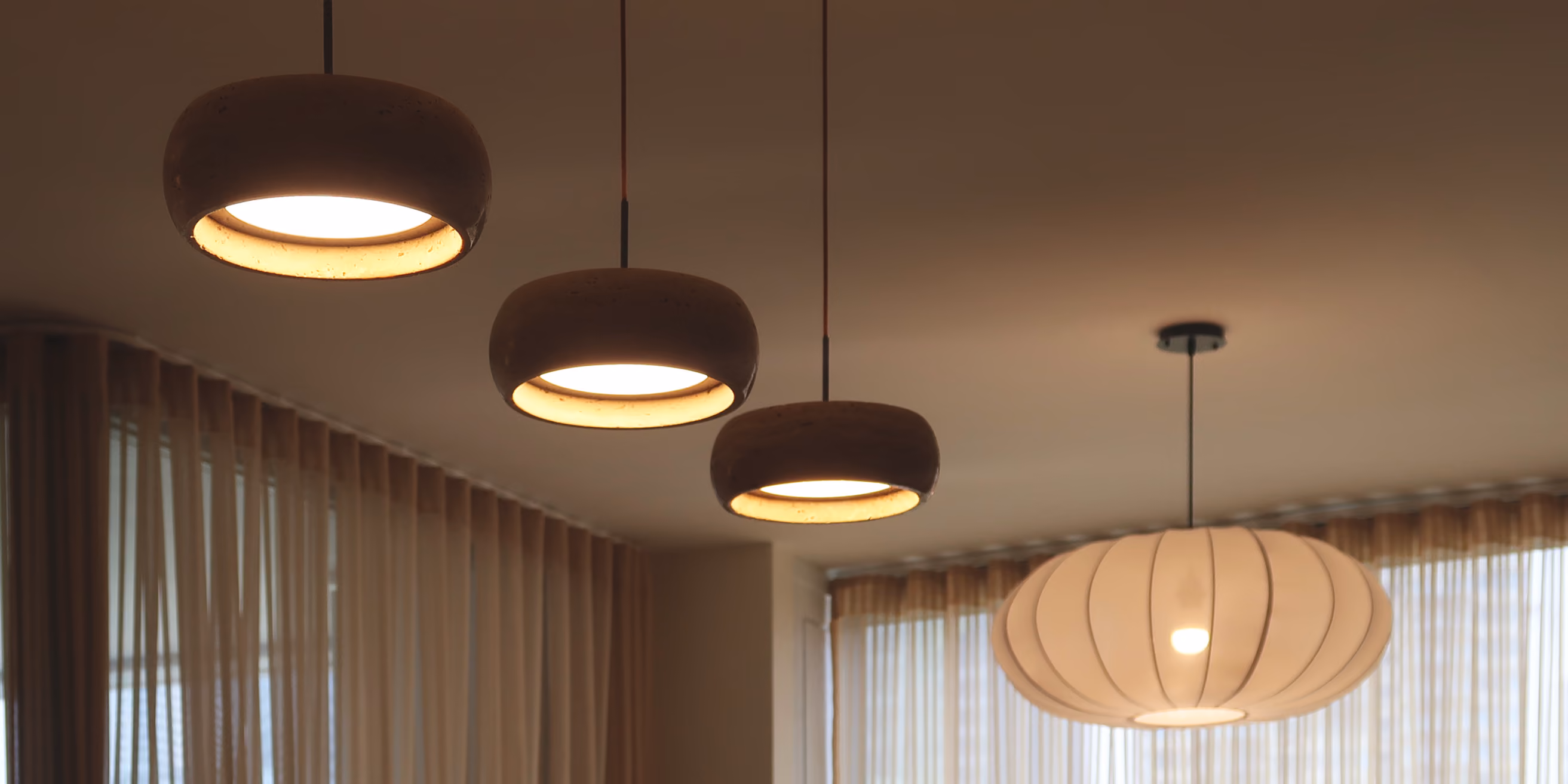 Three round pendant lights with warm glow and one large white lantern-style ceiling light. T.M. Kawpeng