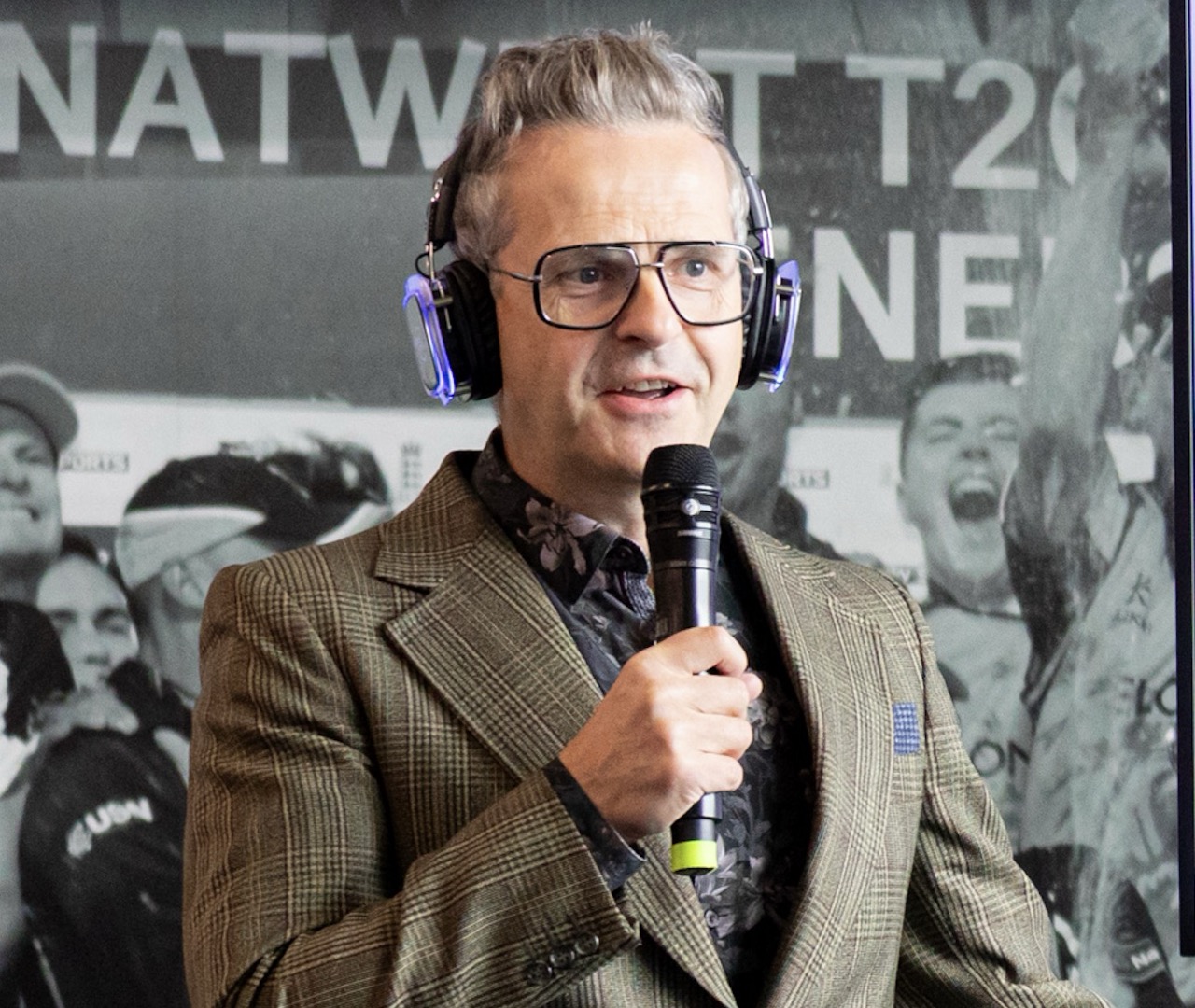 Anthony Tattum wearing headphones and speaking into a microphone in front of a NatWest event backdrop