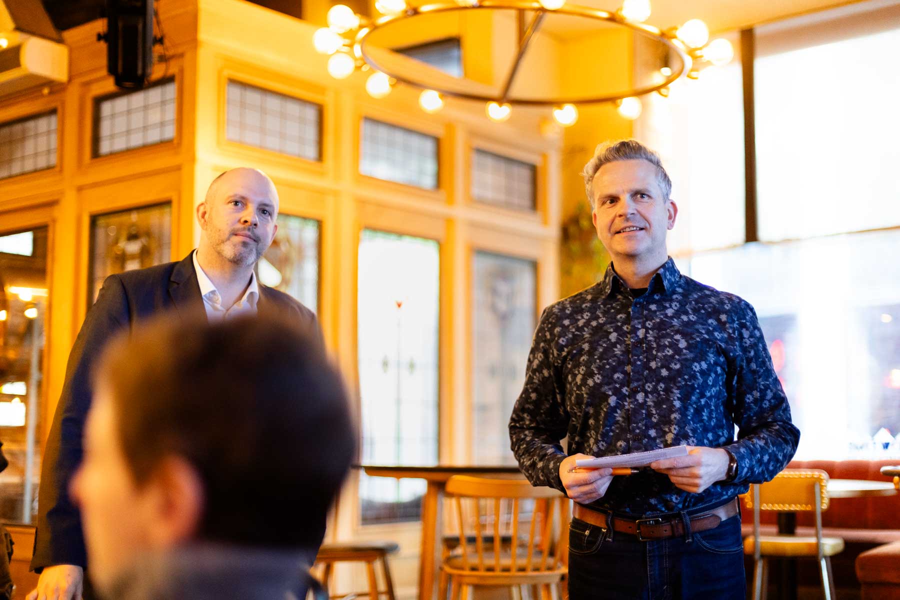 Anthony Tattum speaking to attendees at an informal roundtable event in a warmly lit venue