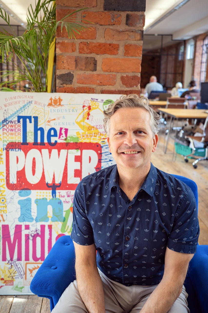 Anthony Tattum seated in front of The Power in the Midlands artwork