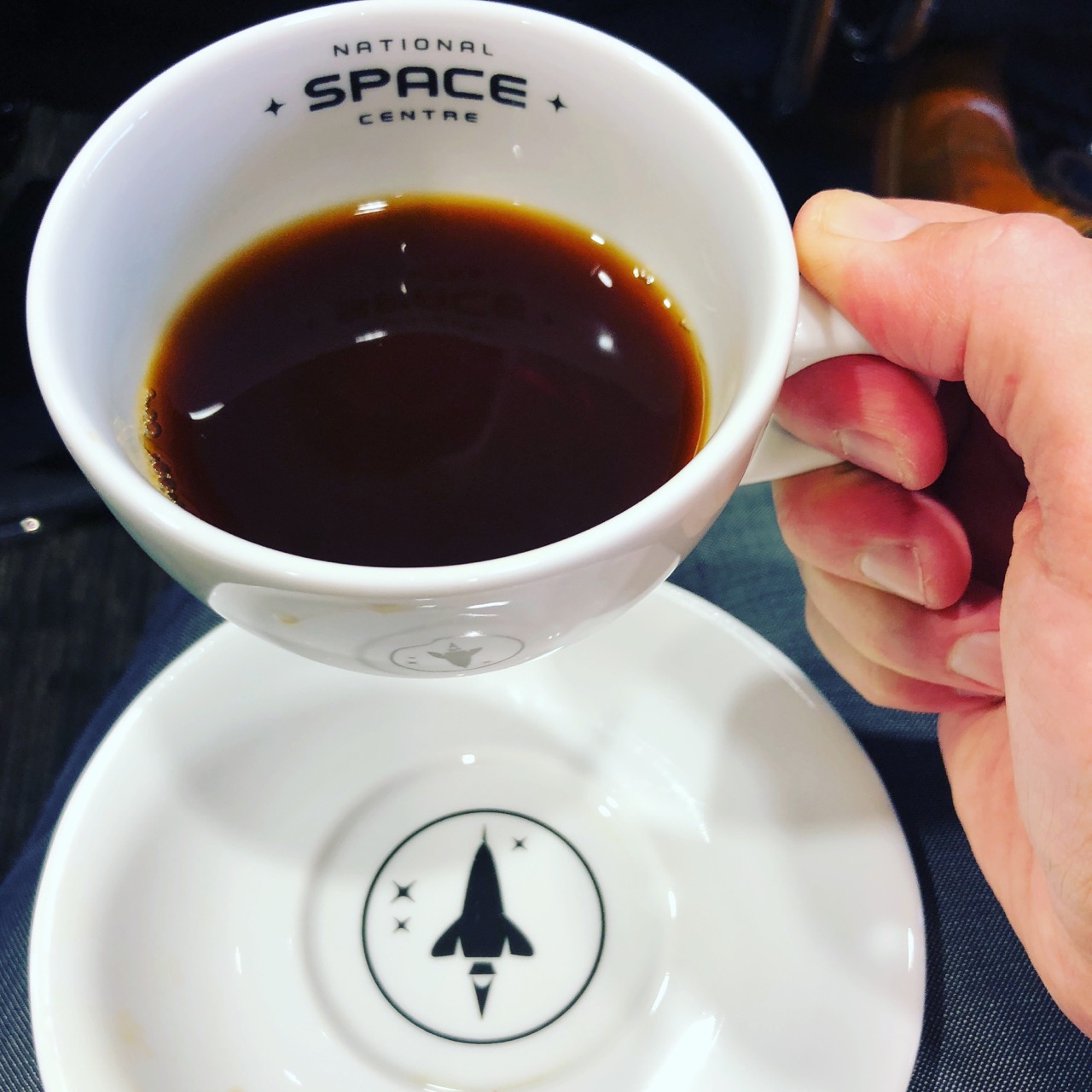 A cup of black coffee in a National Space Centre cup and saucer