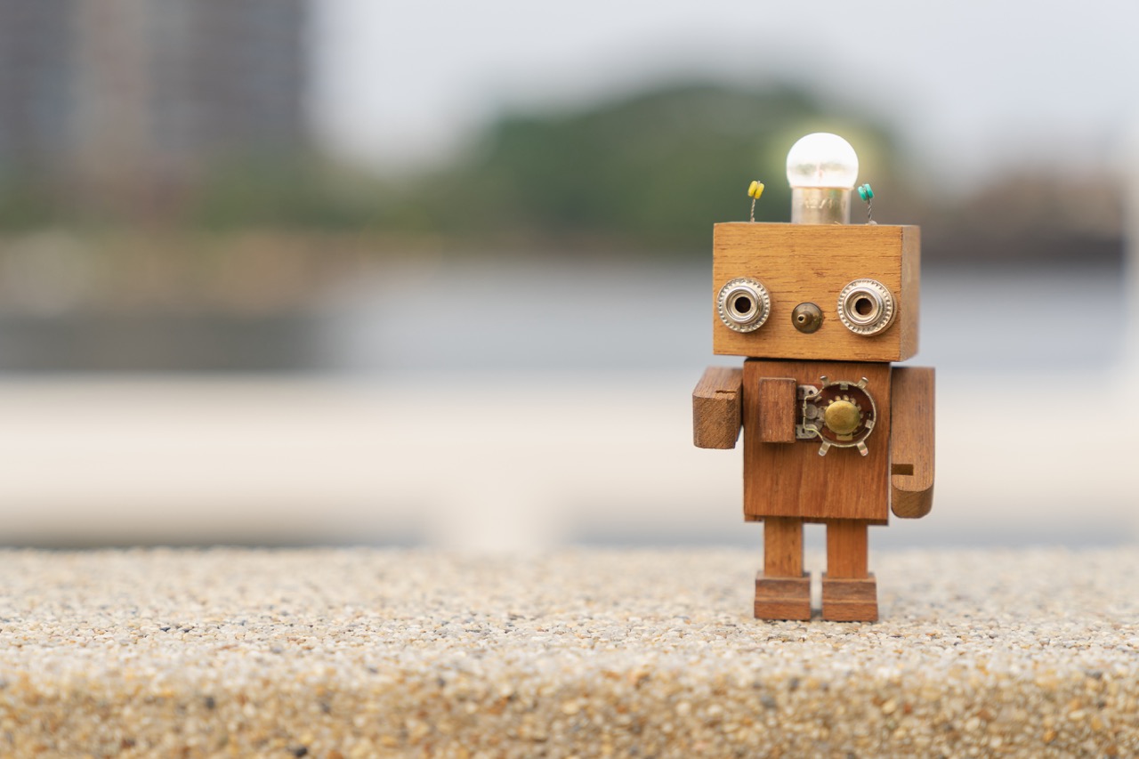 A small wooden robot with a light bulb on its head