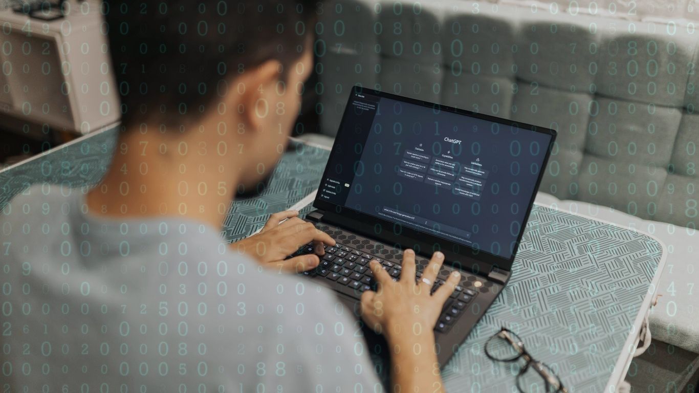 A man typing at a laptop with an AI chat tool open, with lines of code overlaid on the image