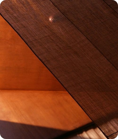 Close-up of intersecting wooden surfaces with warm lighting and visible wood grain texture.
