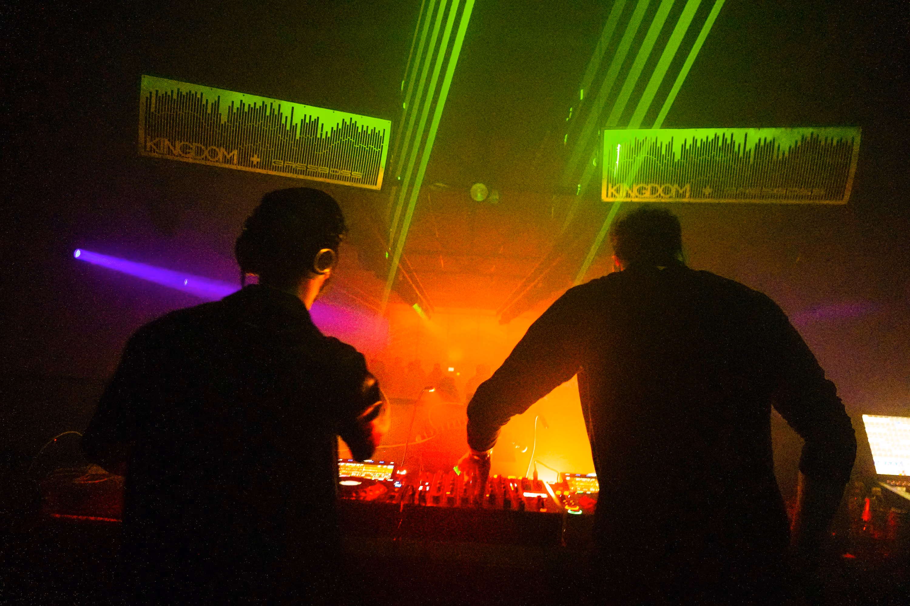 Saint Stratus perform at a club with green laser lights and an orange foggy background.