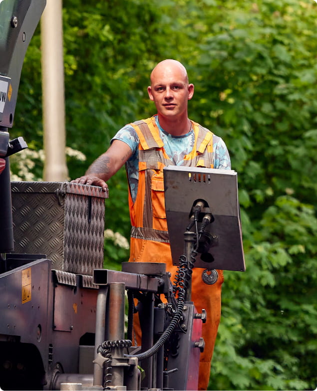 Collega van Asfaltbouw aan het werk bij de asfaltmachine