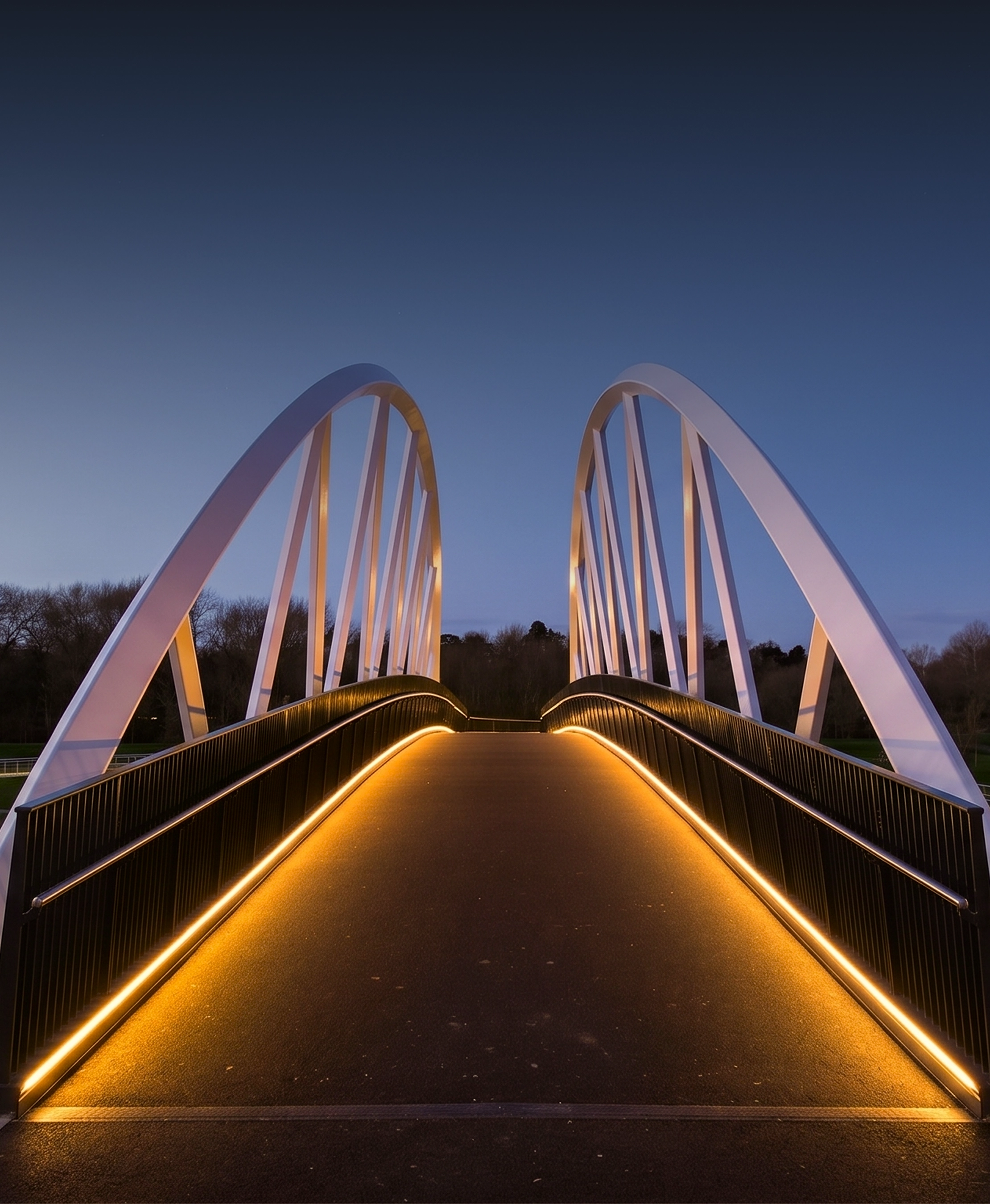 Modern pedestrian bridge with white arches and orange LED lights along the sides at dusk.