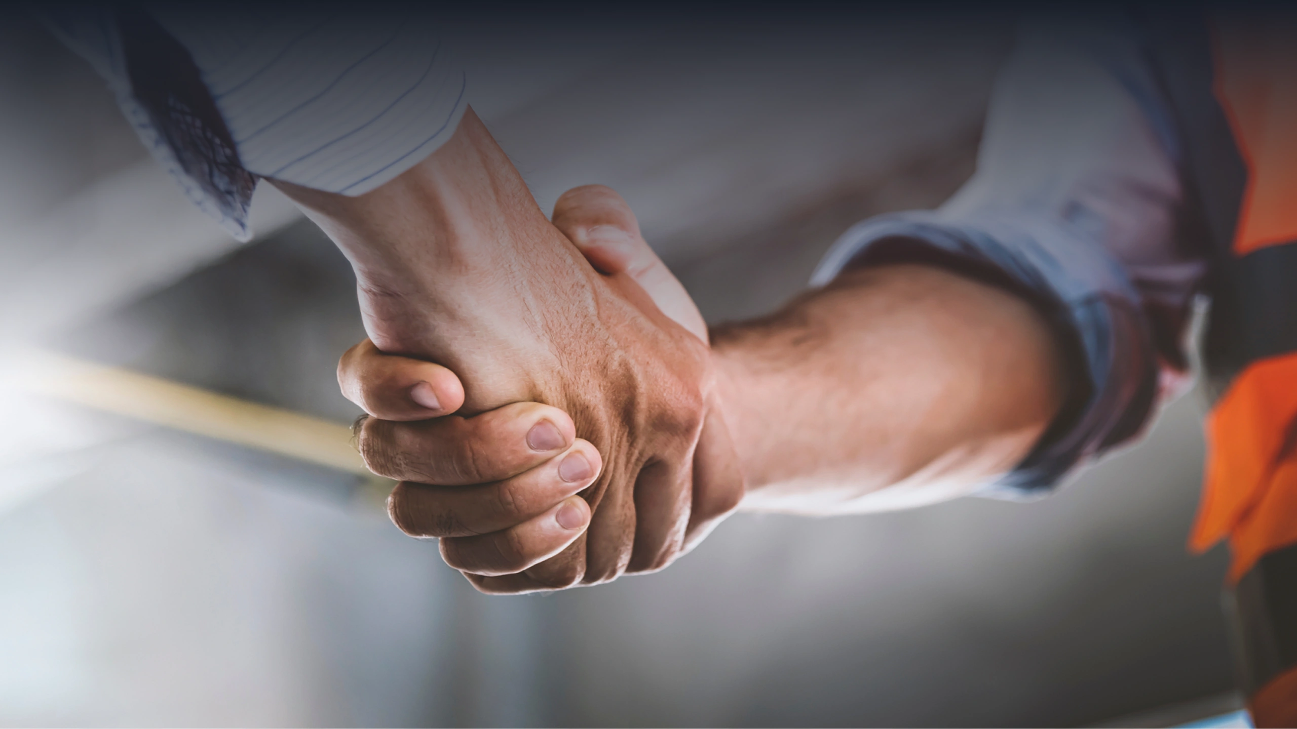 Close-up of two people shaking hands in a business or work setting.