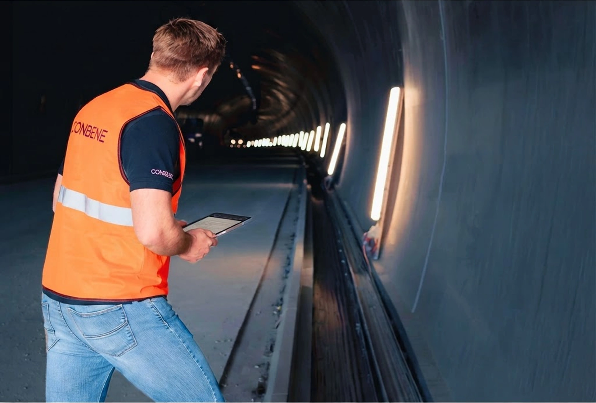 CONBENE advisor in an orange vest inspecting a tunnel while holding a tablet.