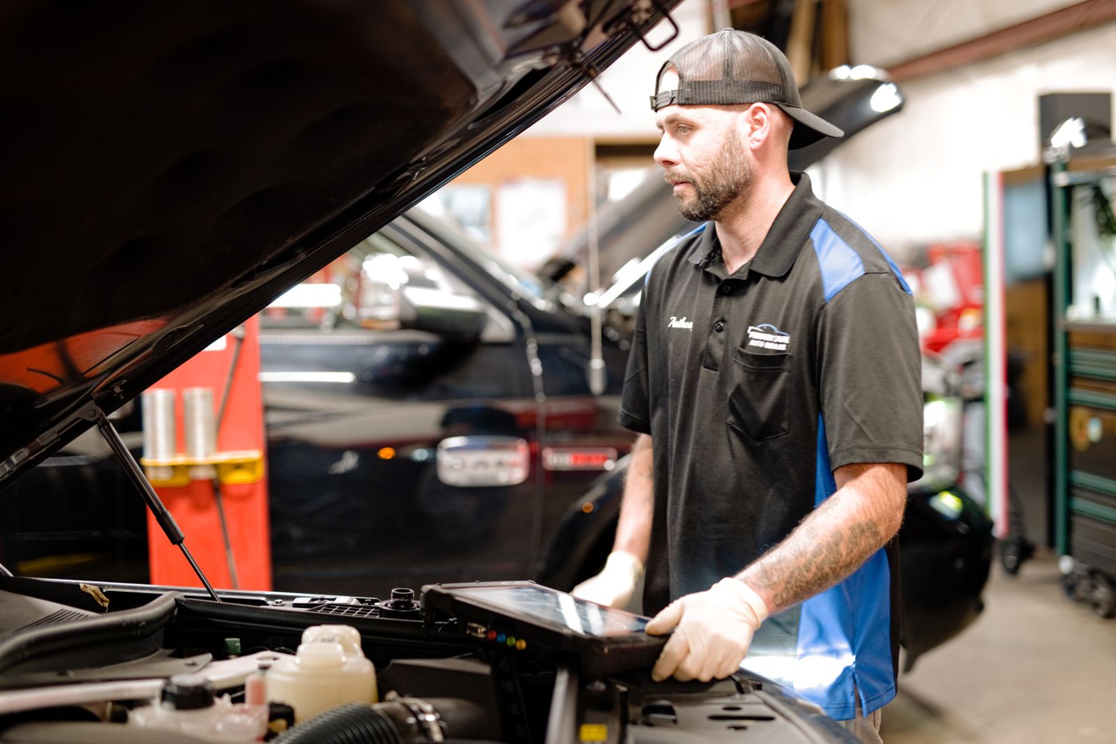 Primary Care Auto technician diagnosing a vehicle with a scan tool in the service bay