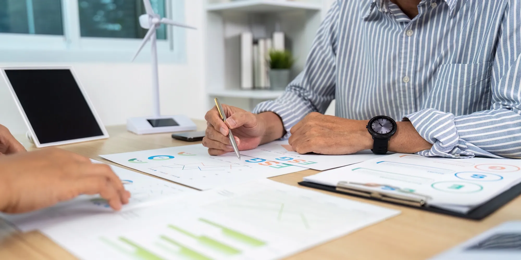 Person analysiert Energiespar-Dokumente mit Grafiken und Diagrammen am Tisch.