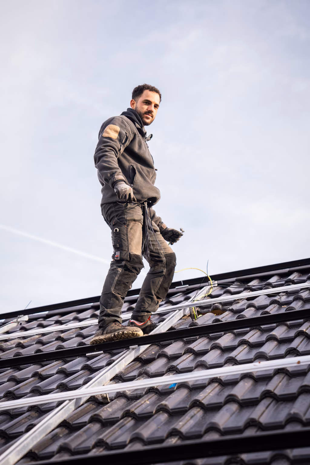 Mitarbeiter der PV Hessen GmbH steht auf einem Einfamilienhaus, wo gerade eine Solaranlage montiert wird