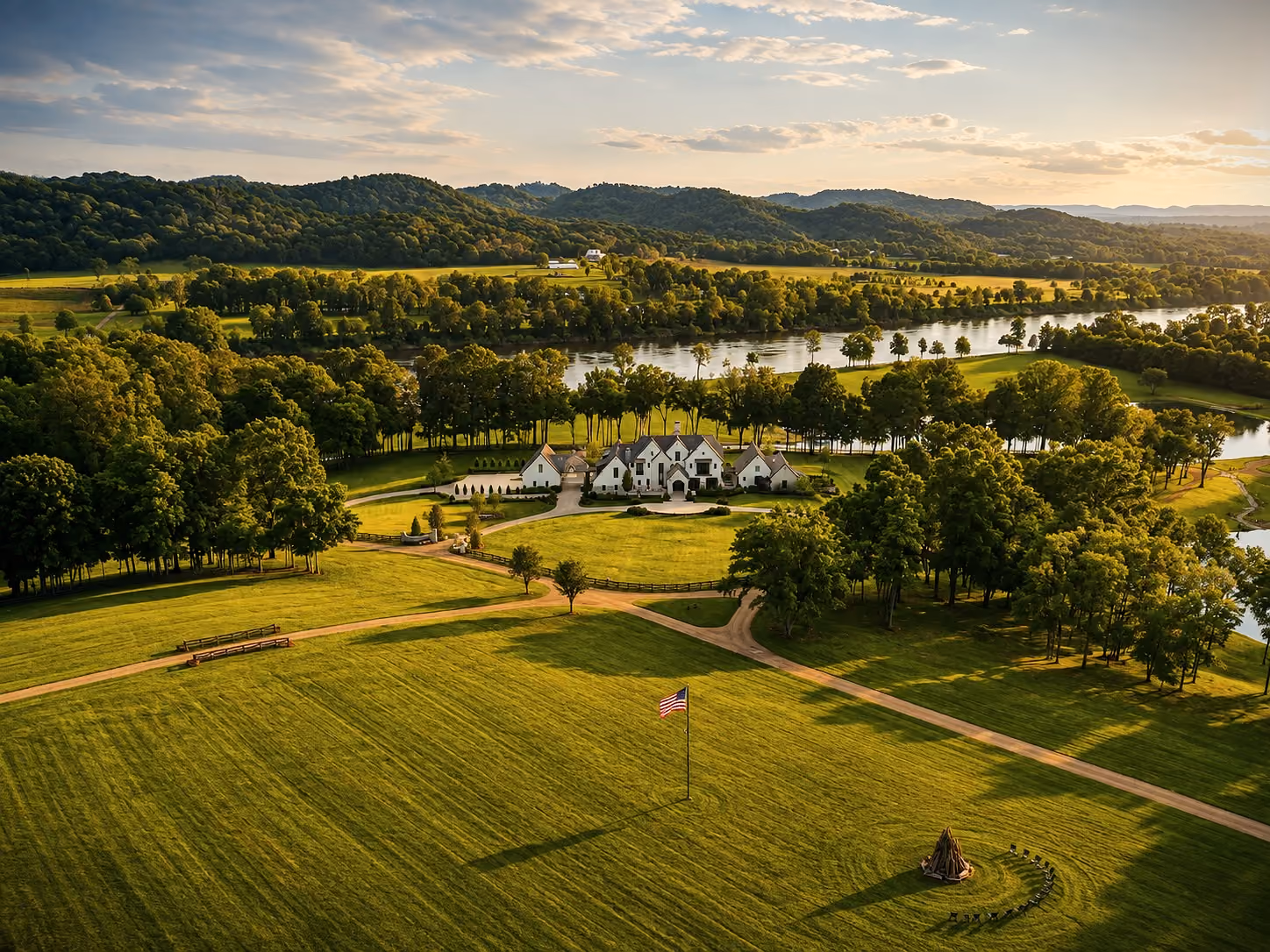 Aerial view of a Castle Homes estate along the river at 8021 River Road Pike, with a circular driveway and firepit lawn.